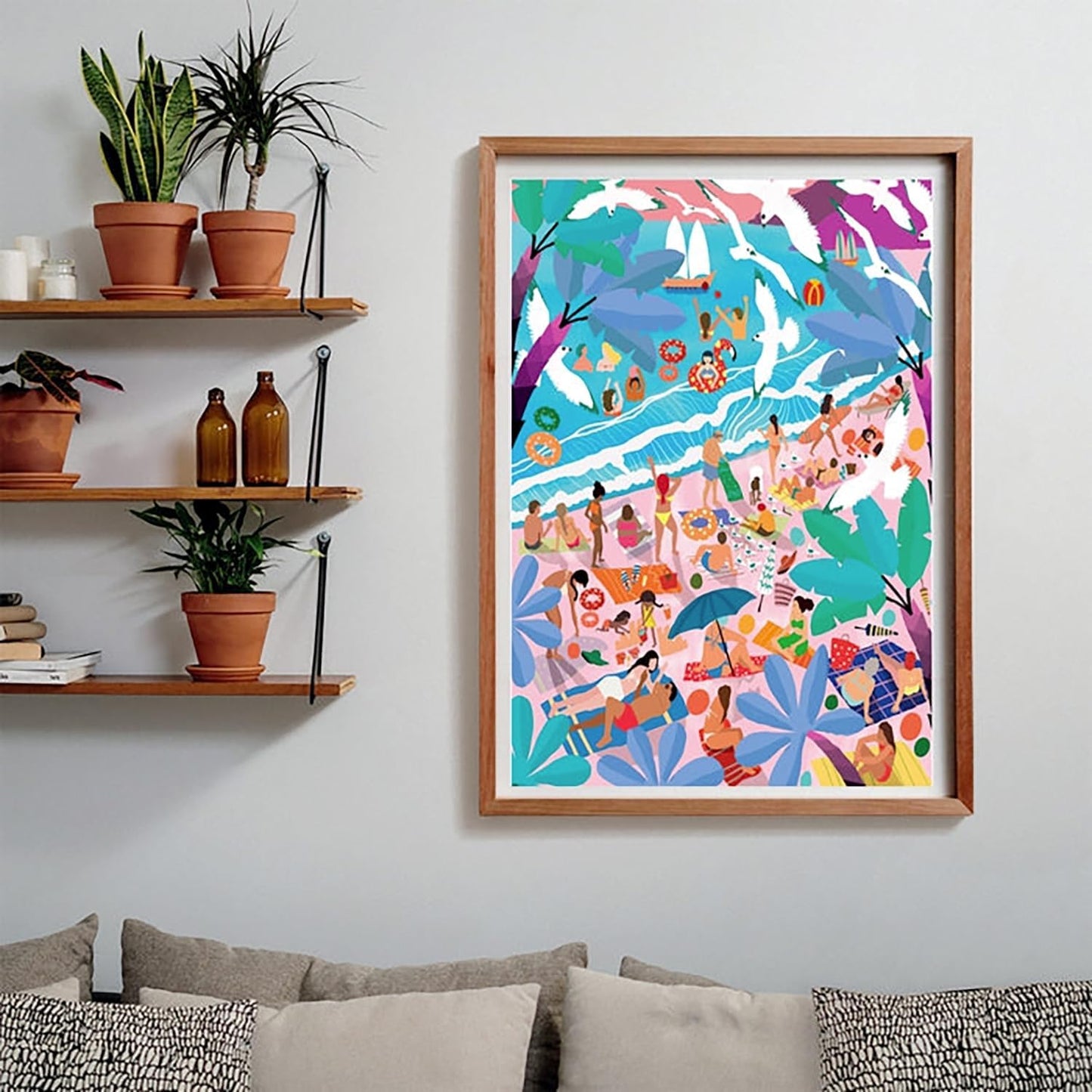 A vibrant, framed illustration of a crowded tropical beach with people, boats, and seagulls hangs above a couch and shelves with plants