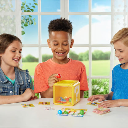 Smiling children playing an Super Mario Question Block game. A boy holds a red token over a yellow question mark cube