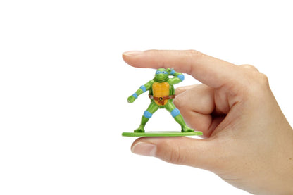 Miniature green Teenage Mutant Ninja Turtle Leonardo action figure held by a hand against a white background