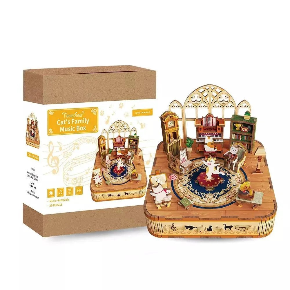 Detailed wooden 3D puzzle music box depicting a cat family scene with dancing figures, displayed next to its brown packaging