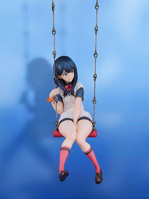 Anime figure of a girl with black hair sitting on a red swing wearing a white and blue school uniform and pink socks