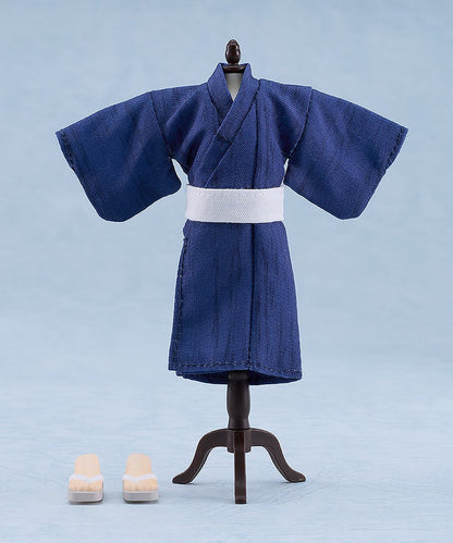 Doll-sized dark blue yukata with white obi on a mannequin, next to two tiny geta sandals