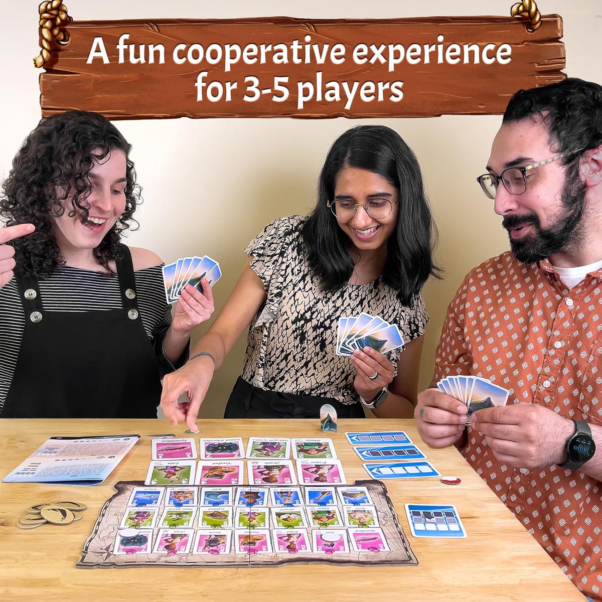 Three happy people playing a cooperative board game with cards &amp; map on a wooden table