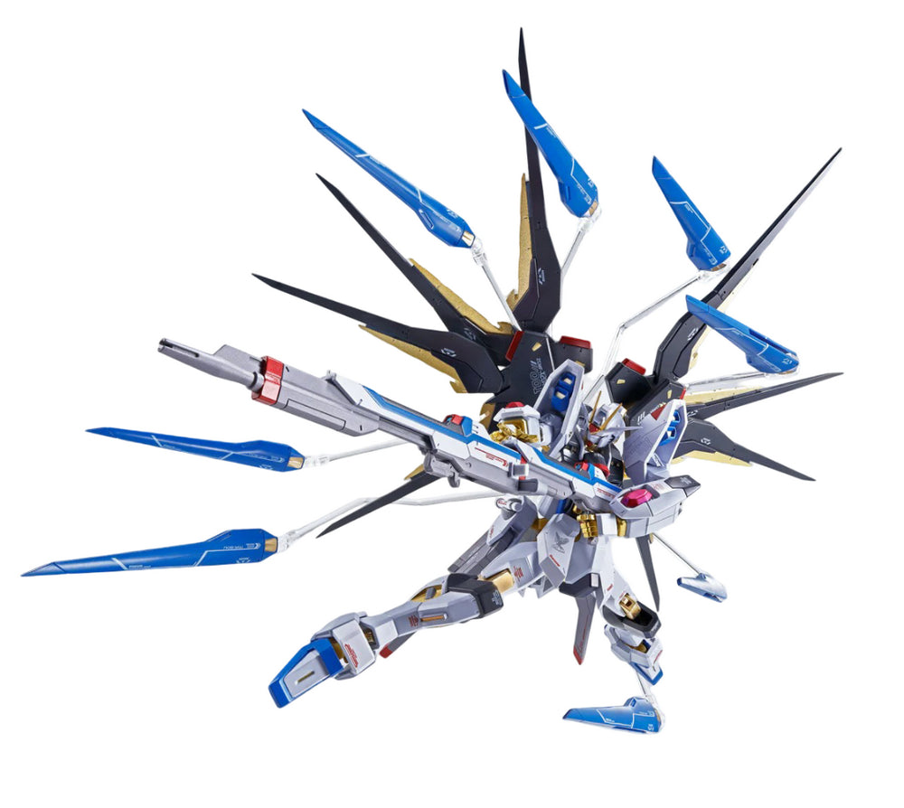 A white, blue, and gold Strike Freedom Gundam model in a dynamic pose, holding a rifle with its large winged backpack and deployed weapons