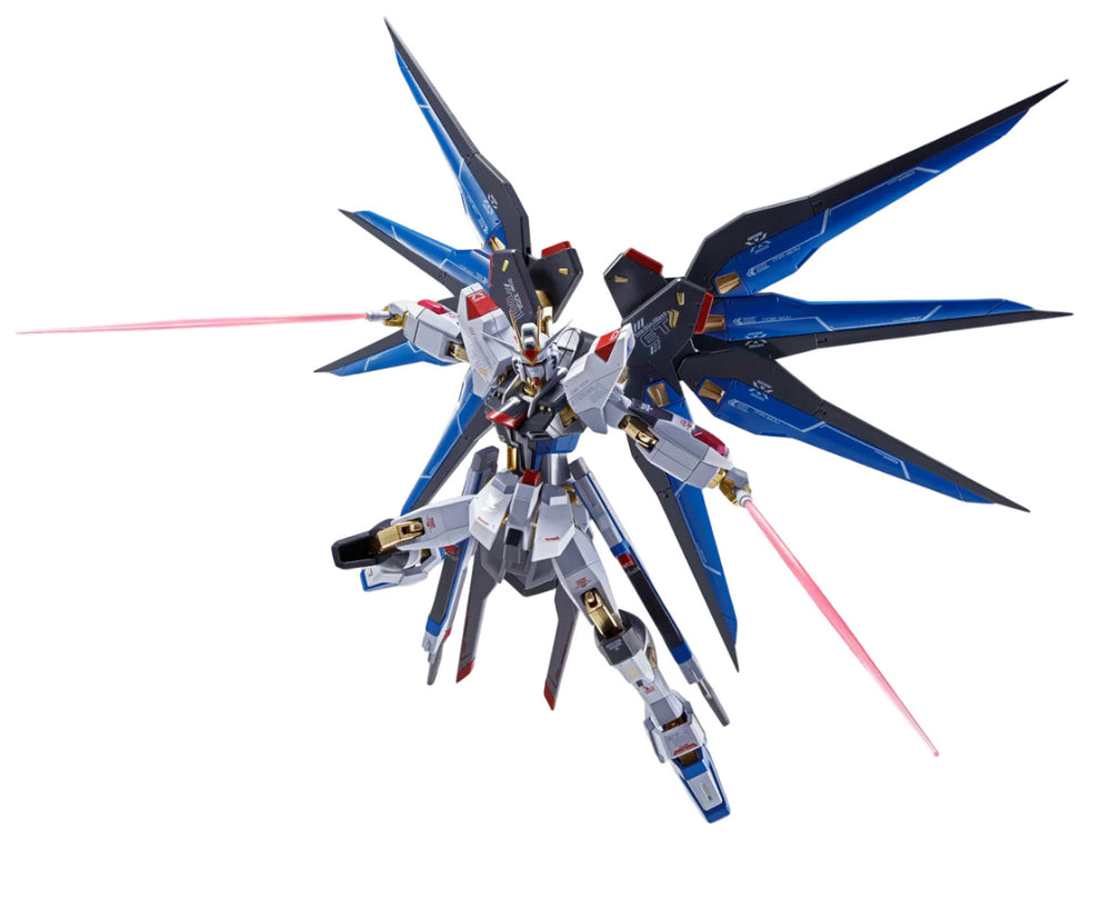 White, blue, and gold Freedom Gundam model with large black and blue wings, wielding two pink beam sabers