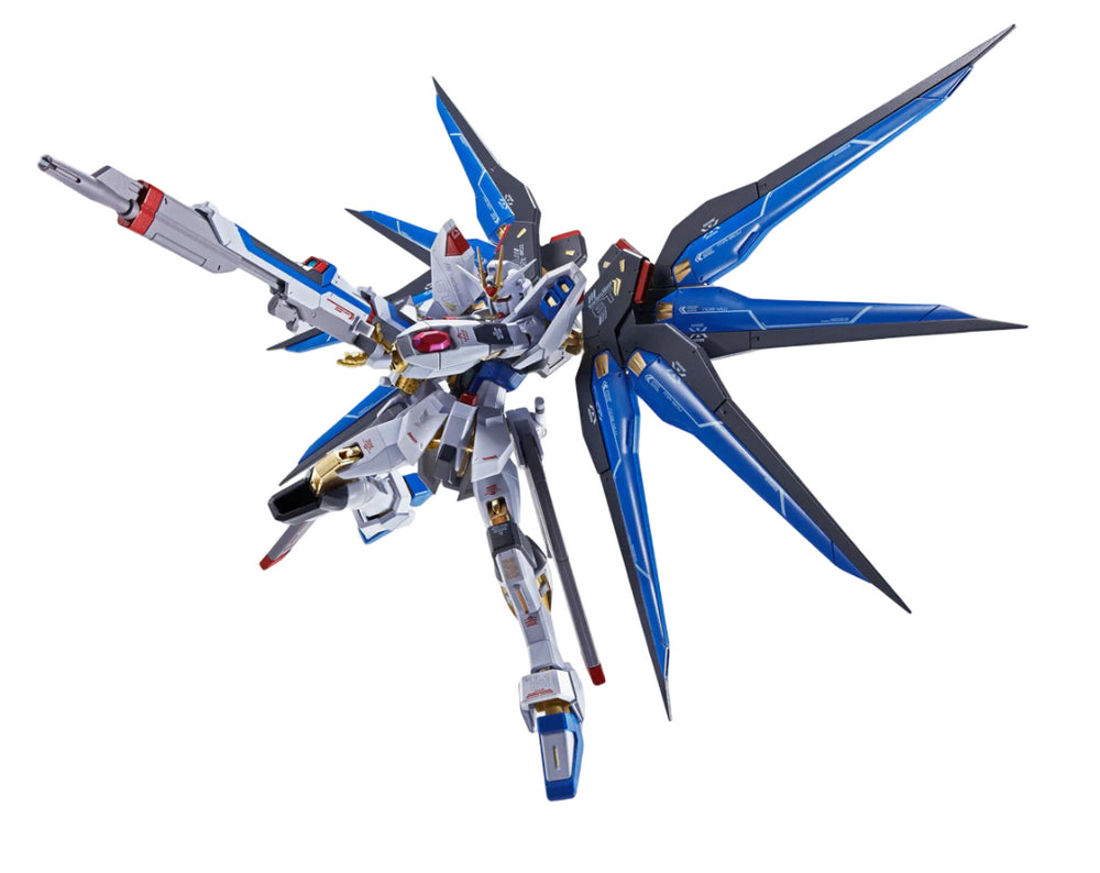 White, blue, and gold Gundam model with large deployed blue wings, dynamically holding a rifle