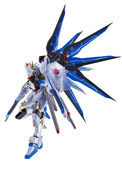 White, blue, and gold Strike Freedom Gundam model with large, spread blue wings, holding a rifle