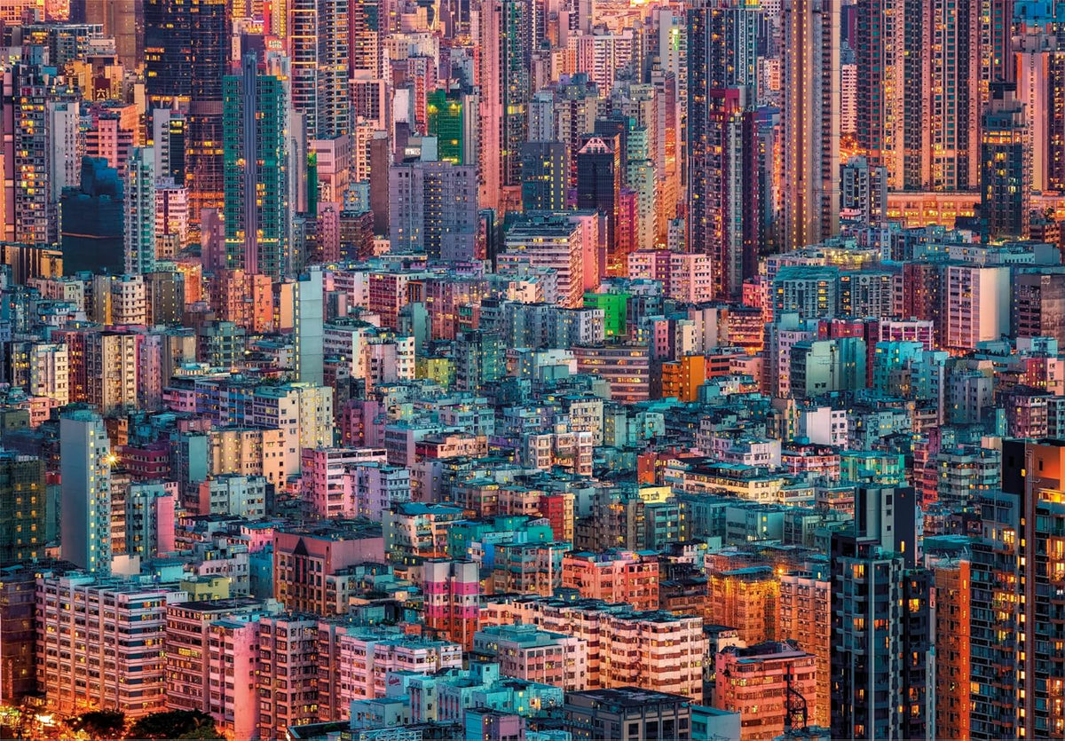 A dense cityscape of colorful high-rise buildings, glowing with many illuminated windows in the evening light