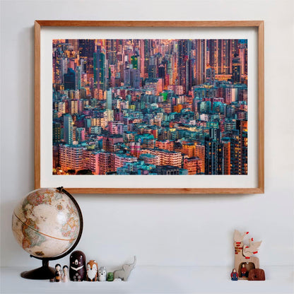 Framed photo of a dense, colorful city skyline at dusk, with a globe and figures on a shelf below