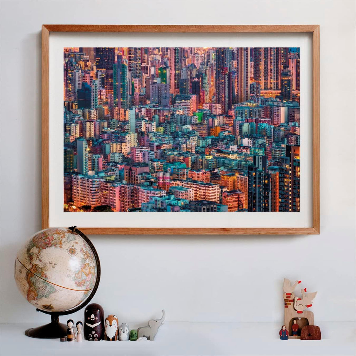 Framed photo of a dense, colorful city skyline at dusk, with a globe and figures on a shelf below