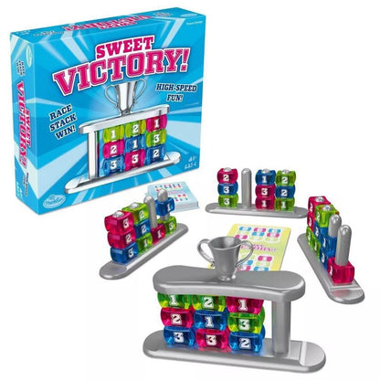 Sweet Victory! board game box and pieces: colourful translucent numbered blocks stacked on grey bases with silver posts, plus a silver trophy