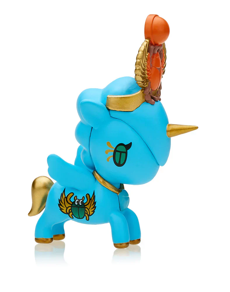 A blue winged unicorn toy with golden horn, wings, and Egyptian scarab motifs. An orange winged scarab rests on its head