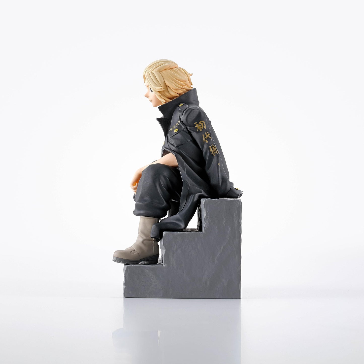 Blond anime figure in black jacket with gold Japanese script, sitting on gray steps