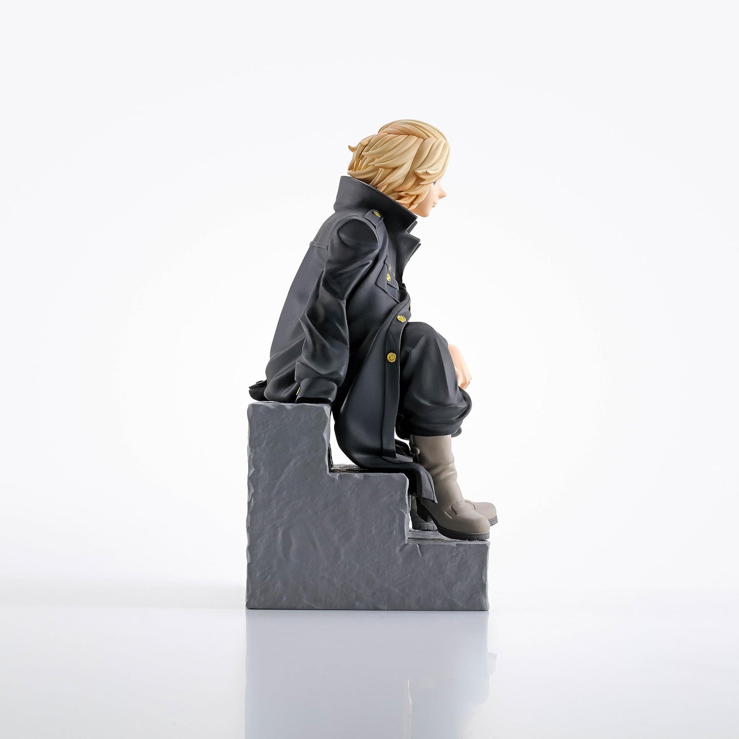 Blonde-haired anime figure in a dark long coat with gold buttons, sitting on gray steps, looking right