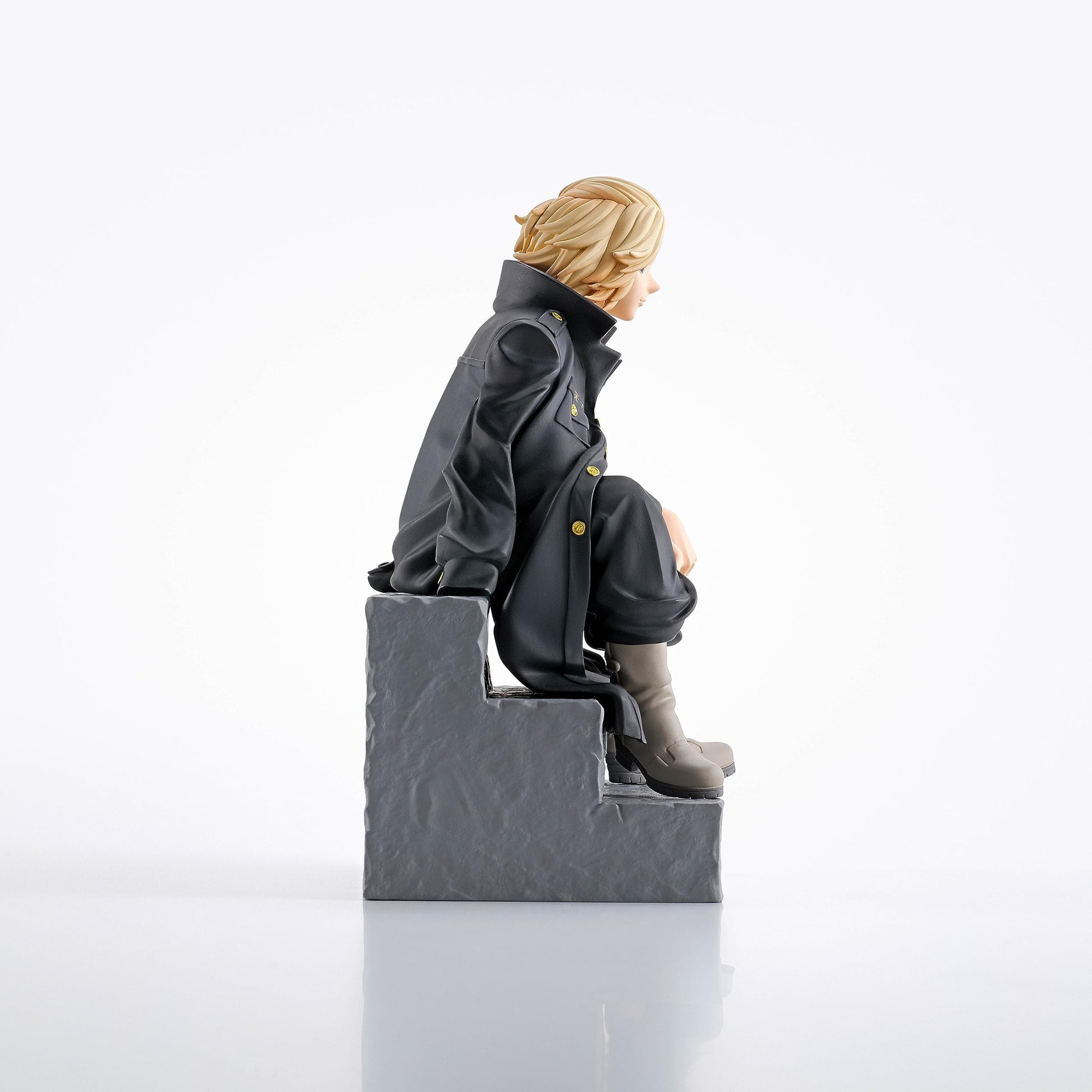 Blonde-haired anime figure in a dark long coat with gold buttons, sitting on gray steps, looking right