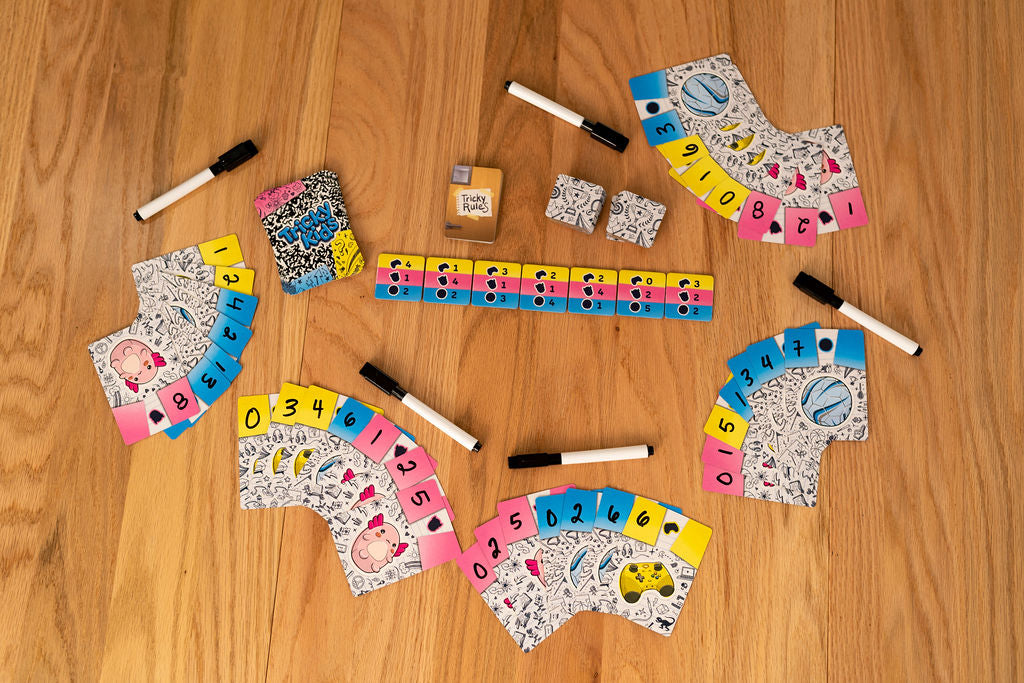 Card game set up on a wood table, showing numbered fan cards, markers, and rule tiles for "Tricky Rules"