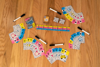 Card game set up on a wood table, showing numbered fan cards, markers, and rule tiles for "Tricky Rules"