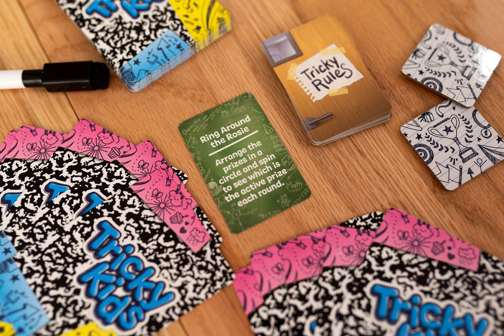 Tricky Kids card game components: rule cards, prize tokens, and a marker displayed on a wooden table