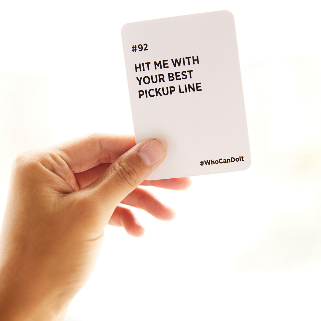 Stack of Who Can Do It card with pickup line challenge in hand