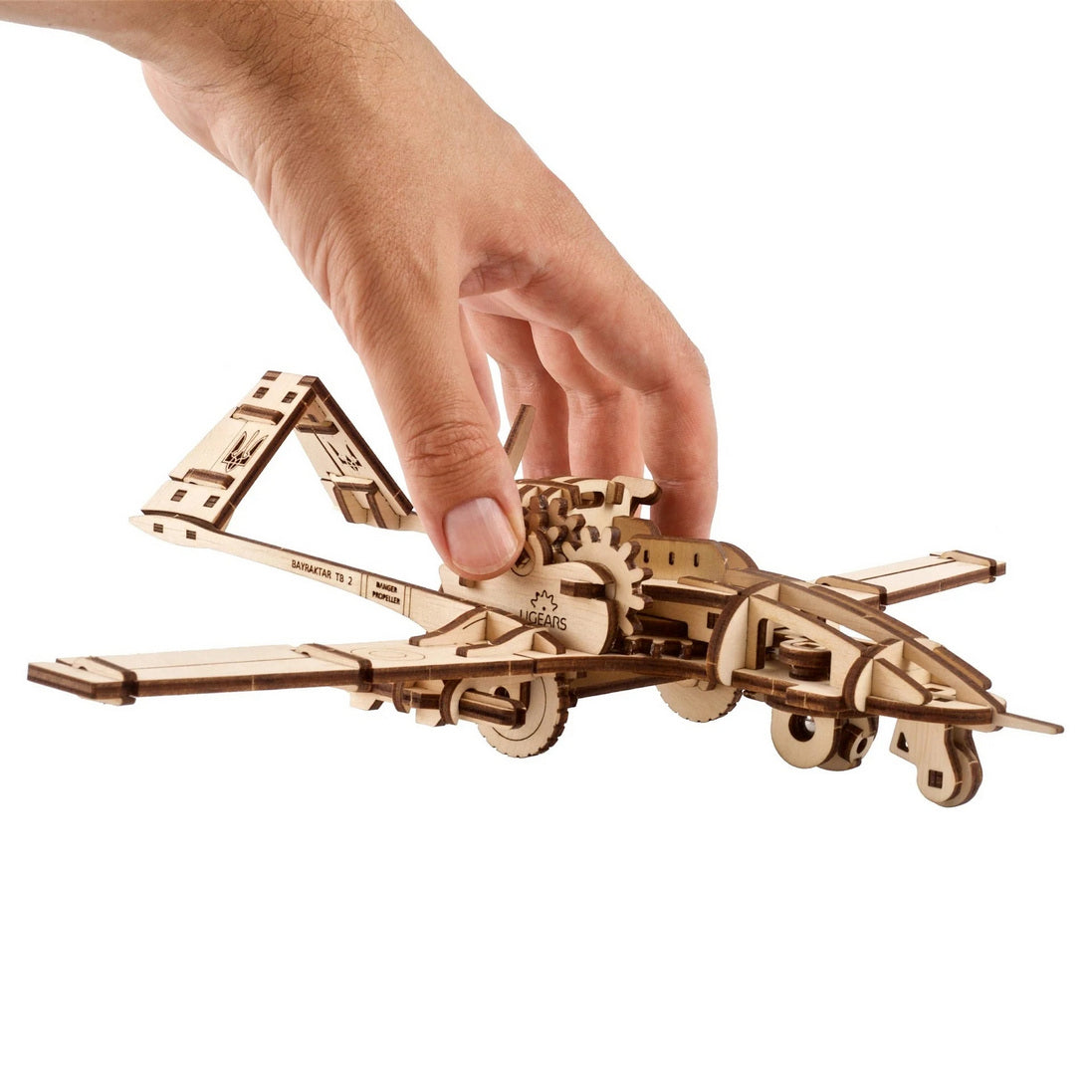 Hand holding an intricate wooden puzzle model of a Bayraktar TB2 drone