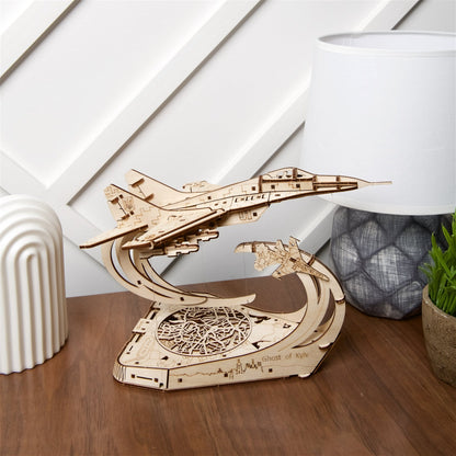 Wooden model of a fighter jet with Ukrainian emblem, displayed on a stand reading "Ghost of Kyiv" on a wooden table
