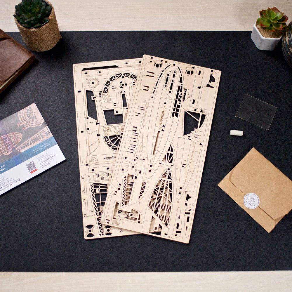 Two laser-cut wooden sheets for a Zeppelin model, with instructions, on a dark desk