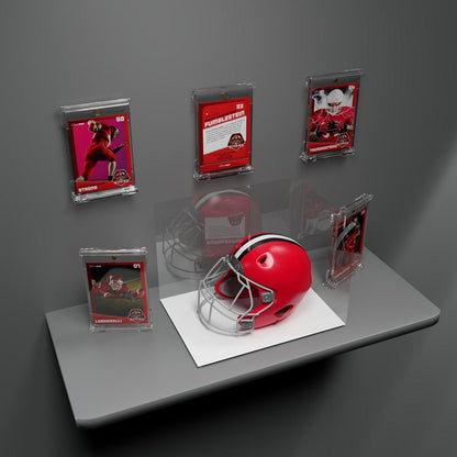 Red football helmet and five framed football trading cards displayed on a gray wall and shelf