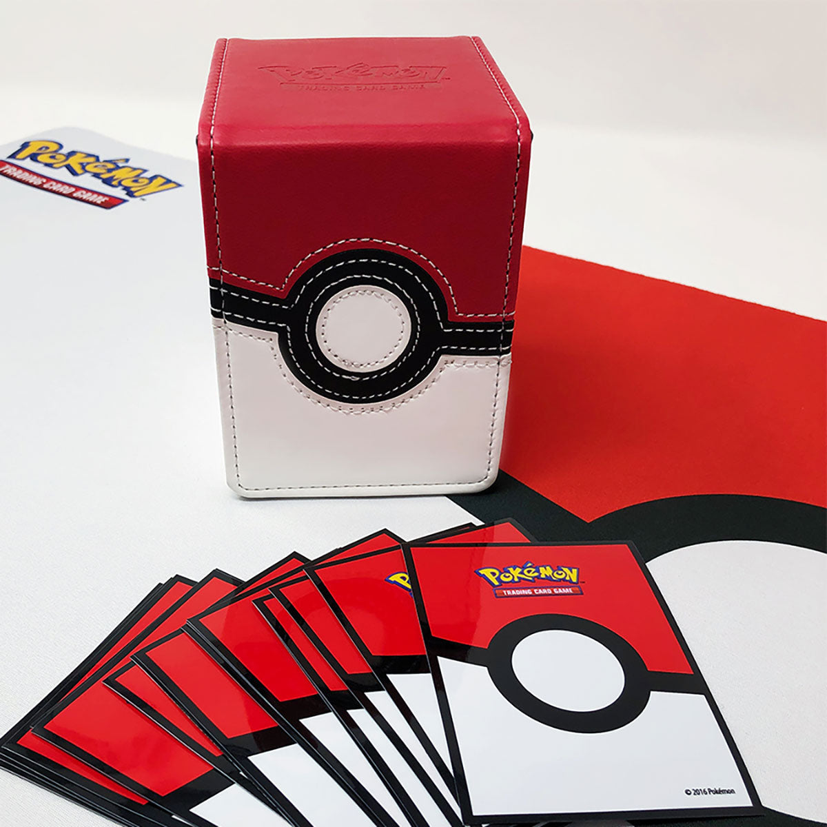 Pokémon Poké Ball deck box with fanned trading cards on a matching playmat