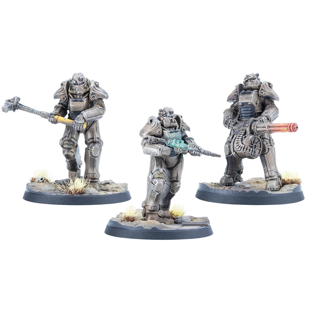 Three Fallout power armor miniatures: one holds a hammer, one a plasma rifle, one a heavy machine gun firing