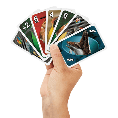 A hand holds a fan of colorful dinosaur-themed playing cards, with a Mosasaurus card prominent