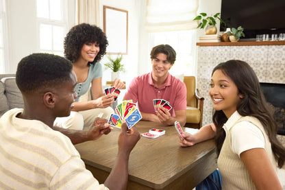 Four smiling young adults play Uno around a wooden table in a bright living room