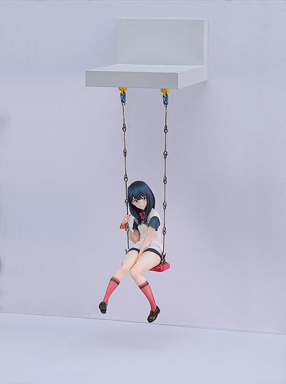 Anime figure of a girl with dark blue hair on a red swing wearing a white shirt with blue trim and dark shorts