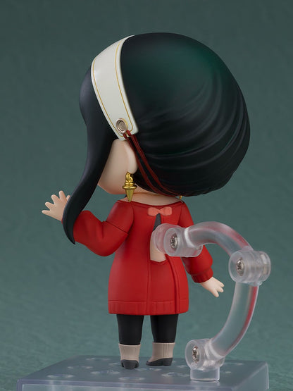 Back of a Yor Forger Nendoroid in a red dress, black hair, white headband, and gold earrings, looking over its left shoulder on a stand