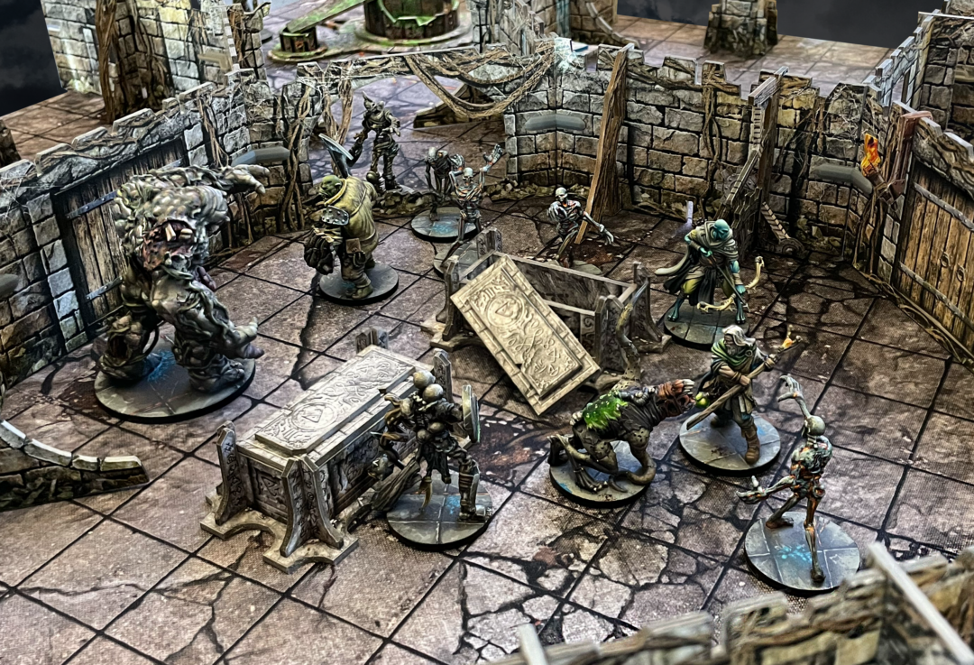 Battle Systems Vaults of Enveron Core Set with modular dungeon terrain and painted fantasy miniatures battling undead including a giant monster skeletons and heroes