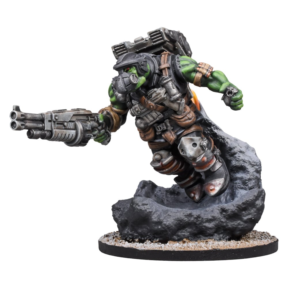 A painted miniature of an armored green Ork with a gas mask, leaping through smoke, holding a multi-barreled gun