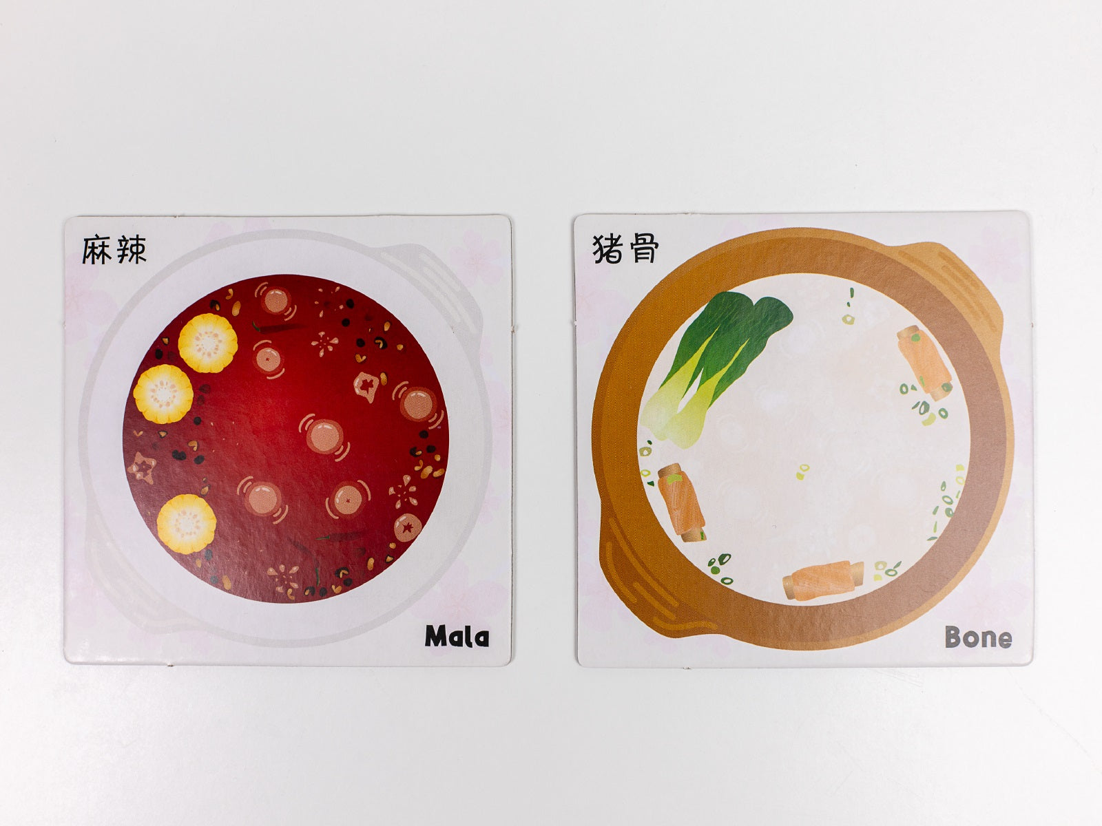 Illustrated cards depicting two hot pot broths: spicy Mala (red) with corn, and creamy Bone broth (white) with vegetables