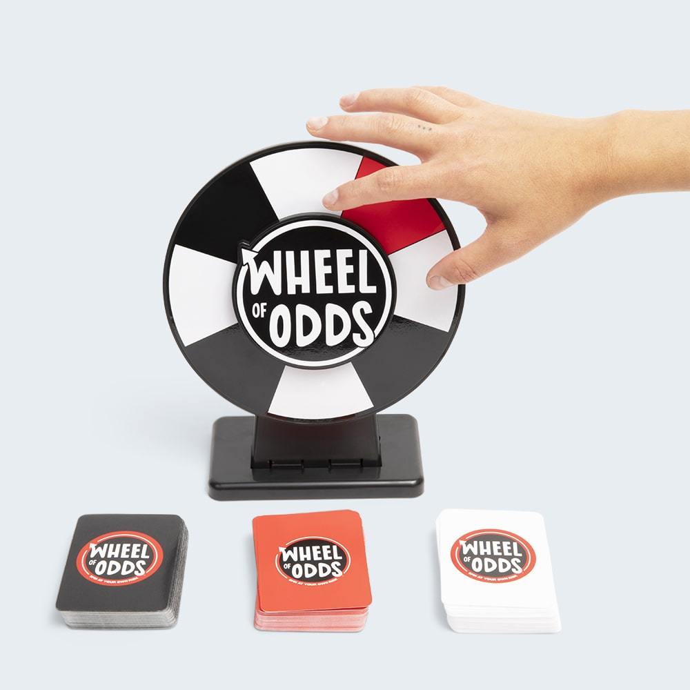Hand spinning the black and white Wheel of Odds game with stacks of cards in black red and white