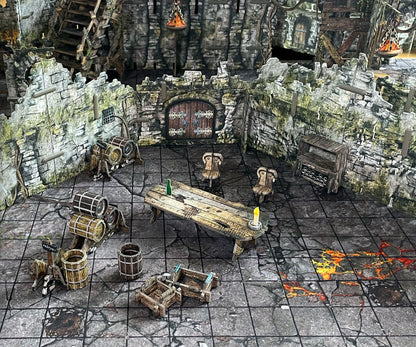 A miniature fantasy tavern setup with stone walls, wooden table, chairs, and barrels. An arched door is central, and the floor has glowing lava cracks.