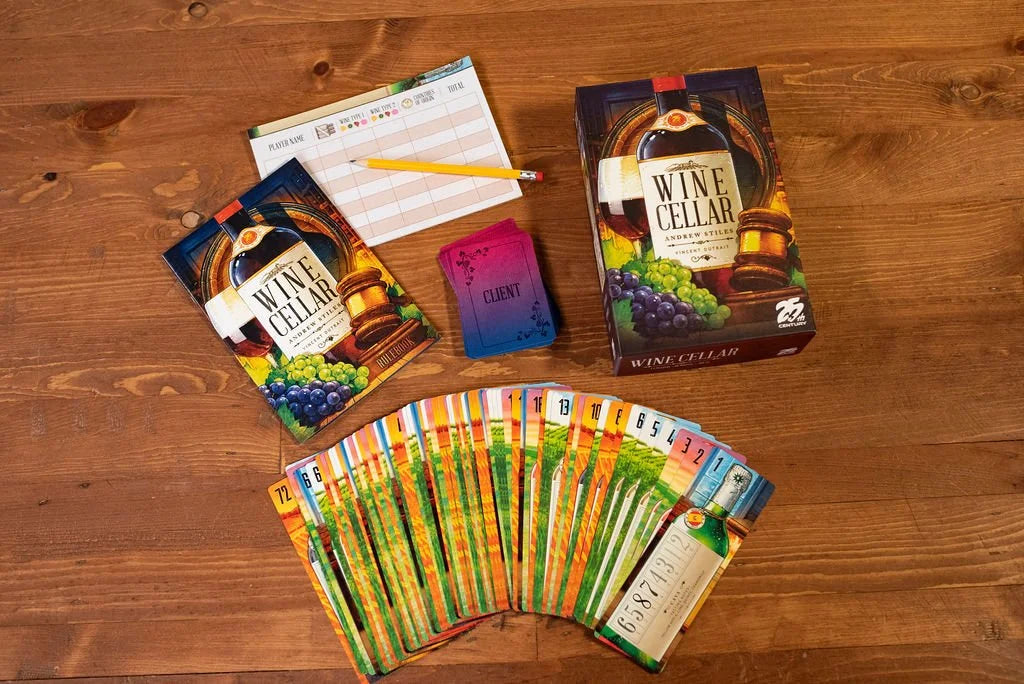 The Wine Cellar board game box, rulebook, scorepad, pencil, and game cards are spread out on a wooden table