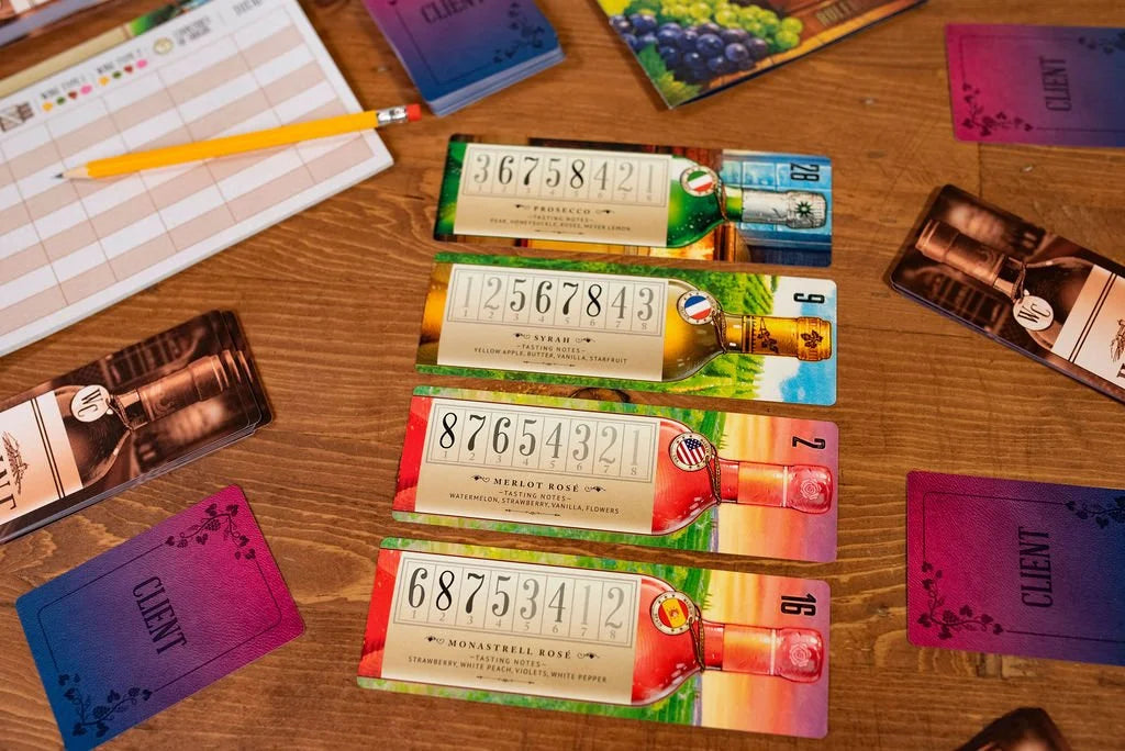 Components of the Wine Cellar board game including wine bottle cards with numbers and names, client cards, a score sheet, and a pencil on a wooden table