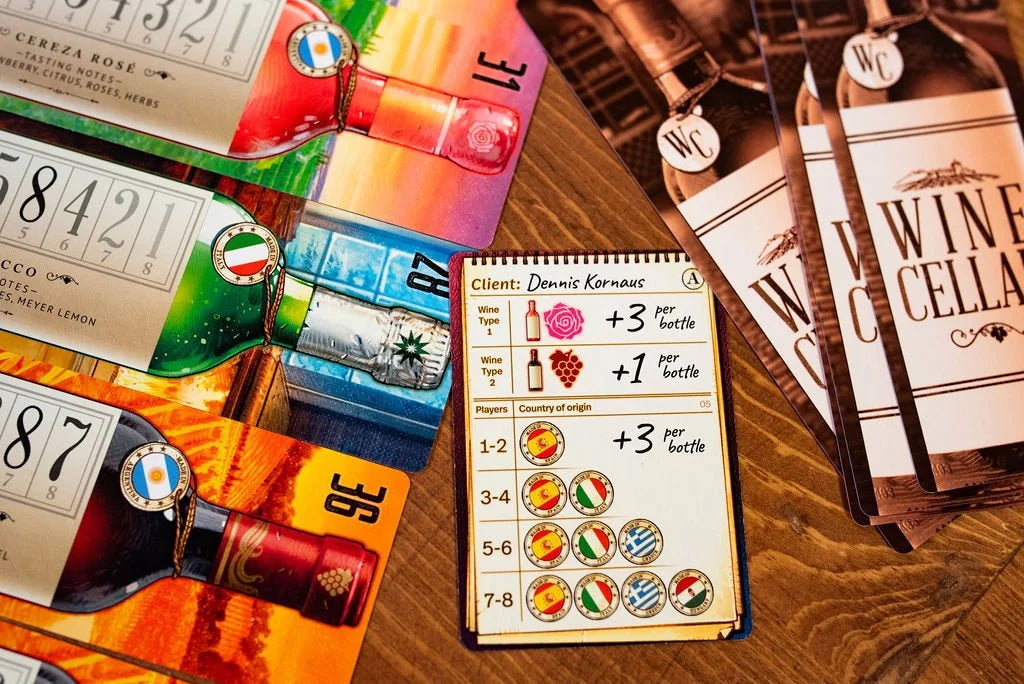 Colorful game cards with wine bottles and country flags, along with a notepad for the Wine Cellar board game, are spread on a wooden surface