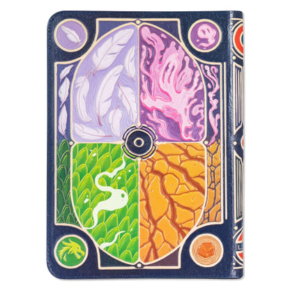 This dark blue faux-leather card binder displays an intricate embossed cover featuring four elemental quadrants: white feathers, pink fluid, green scales, and cracked desert ground