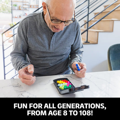 Senior man plays a colourful puzzle game, holding a blue plastic piece over the game grid