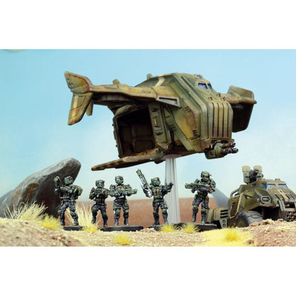 Five miniature futuristic soldiers stand in a desert, with a hovering dropship and armored vehicle