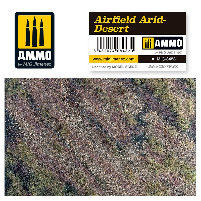 AMMO by MIG Jimenez 'Airfield Arid-Desert' terrain with label. Top-down view of dry, gravelly ground and sparse grass.