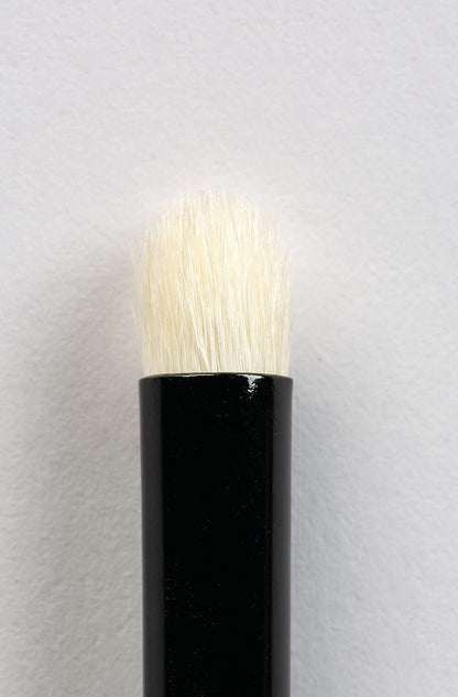 Close-up of a cosmetic brush head with natural white hair bristles and a black handle