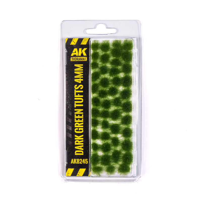 A clear plastic blister pack displays AK Interactive Dark Green Tufts 4mm, featuring many circular dark green model vegetation tufts and a prominent black-and-yellow product label