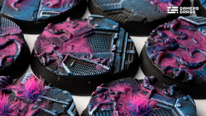 Close-up of miniature bases with dark blue sci-fi plating and vibrant magenta/pink corrupted terrain effects
