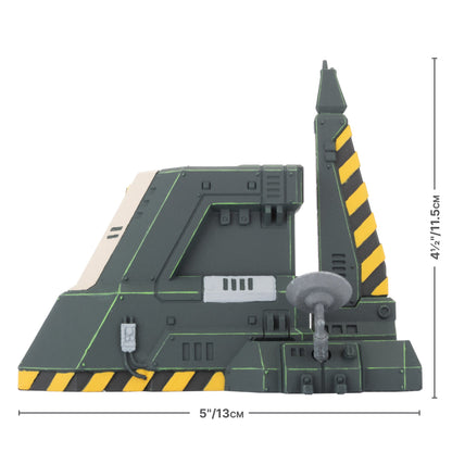 Dark green, angular sci-fi terrain model with yellow/black hazard stripes, a tall tower, and a small gray satellite dish