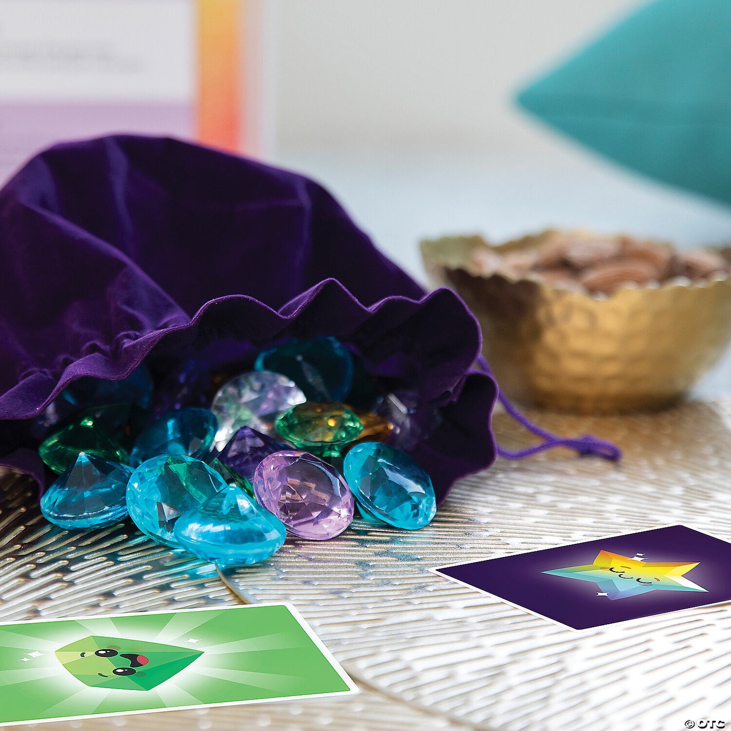 A purple velvet bag spills colorful plastic gems and two game cards on a patterned surface